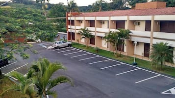 Um edifício com vários andares e um estacionamento em frente.