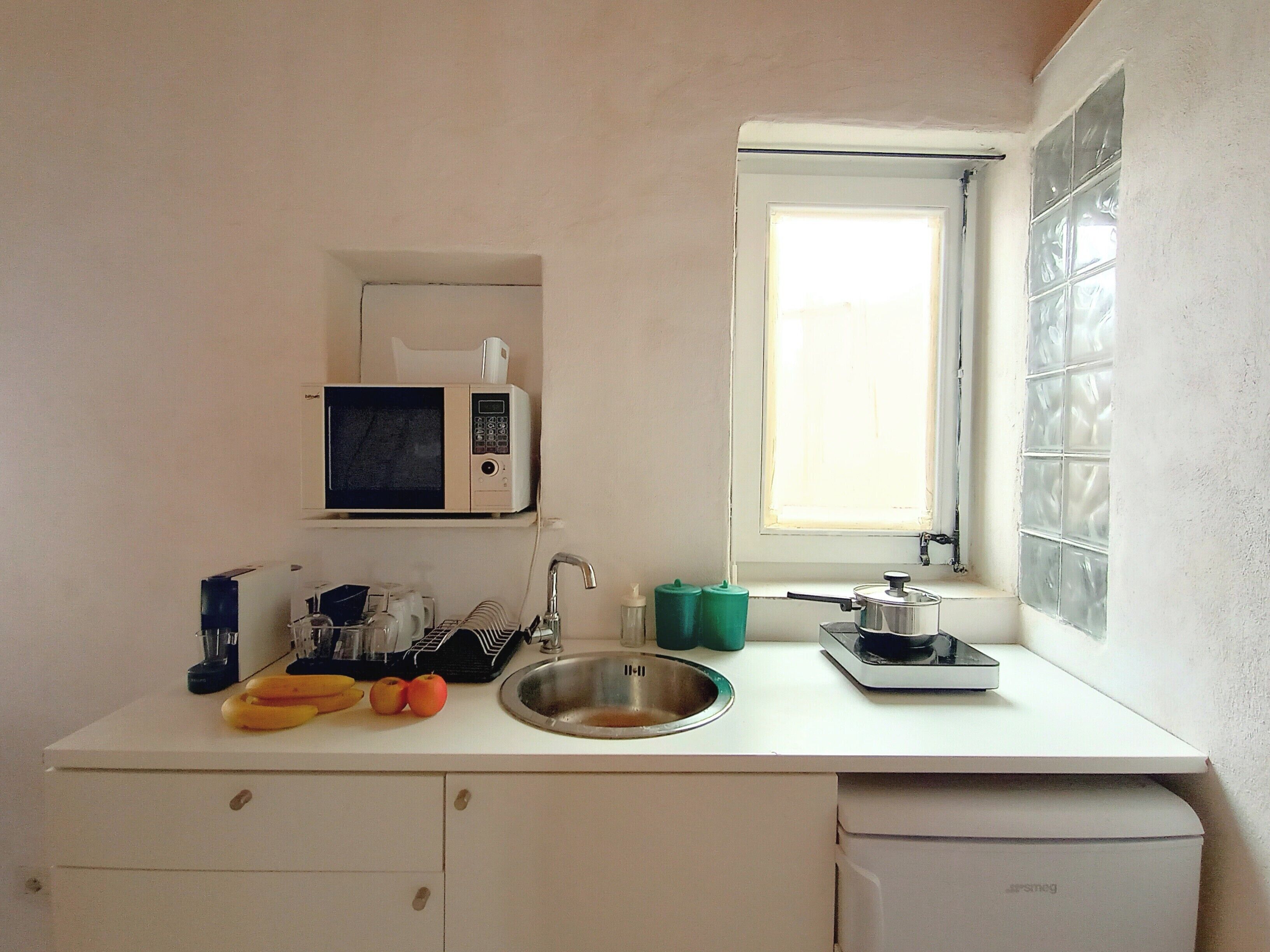 A small kitchen with a microwave, sink, and window.