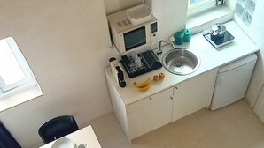 A compact kitchen with a microwave, sink, and small dining table. - Ernesto Home (Palermo)
