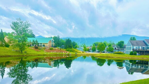 A lakeside view with houses, a clear sky, and a calm reflection on the water. - Loon Mountain Retreat at Lincoln NH (Lincoln)