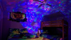 A bedroom with a bed, a ceiling fan, a bunk bed, and a wall with artwork. - Loon Mountain Retreat at Lincoln NH (Lincoln)