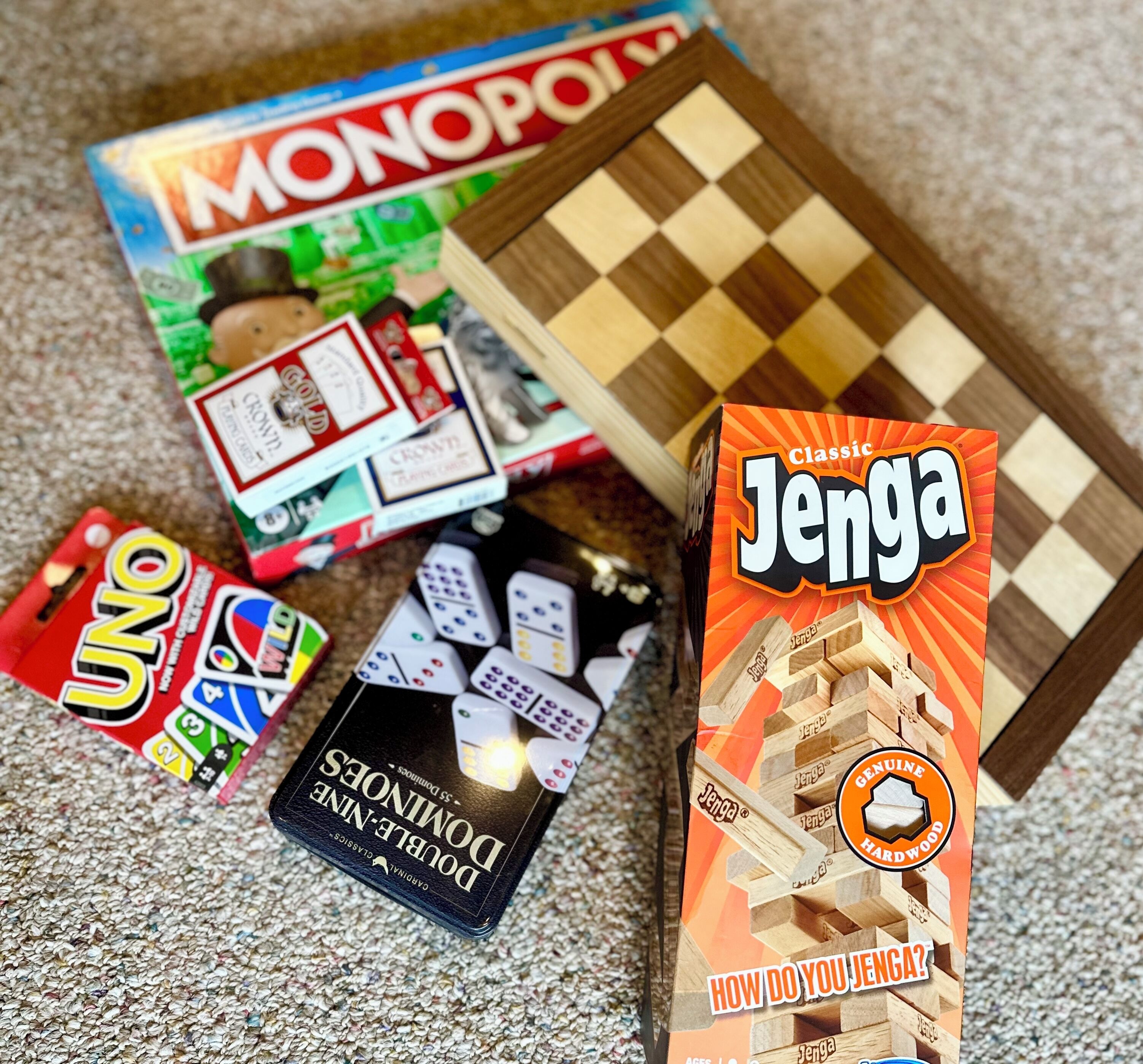 A Monopoly game, UNO, and a Jenga box on a carpet.