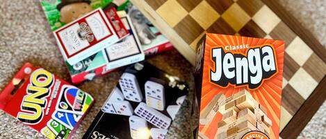 A Monopoly game, UNO, and a Jenga box on a carpet.