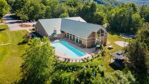A large building with a swimming pool, surrounded by lush greenery and mountains. - Loon Mountain Retreat at Lincoln NH (Lincoln)