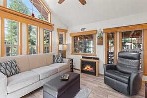Una sala de estar con sofá, reposapiés, chimenea y un sillón de cuero.