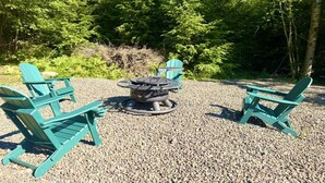 Un braciere circolare con due poltrone Adirondack disposte attorno, su un letto di ghiaia.