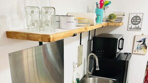 Cucina compatta con piano cottura a induzione integrato, lavandino in acciaio inossidabile e forno a microonde.