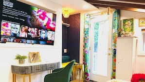 Ett modernt sovrum med en säng, en tv som är monterad på väggen, ett skrivbord med en stol och en färgglad gardin.