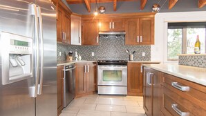 A modern kitchen with stainless steel appliances, wooden cabinets, and a tiled backsplash. - Mariner's Loft Salt Spring Island - 2BDRM - Unit 201 (Salt Spring Island)