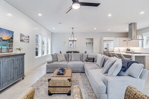 Relax in this spacious living area with a large L-shaped sofa, coffee table, and woven ottoman.