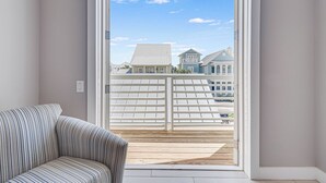 A balcony with a white railing and a view of neighboring houses. - Favor 255 BE (Port Aransas)