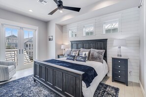 Relax in this serene bedroom with a large bed, nightstand, and dresser, plus a ceiling fan for comfort.