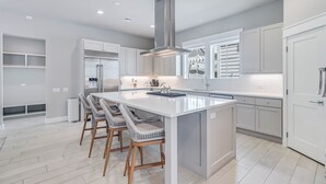 A modern kitchen with white cabinetry, a central island with bar stools, and built-in appliances. - Favor 255 BE (Port Aransas)
