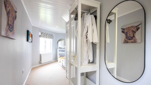 Un couloir avec une armoire blanche, un miroir et des œuvres d’art accrochées aux murs.