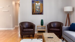A living room with two leather armchairs, a sofa, a coffee table, and a floor lamp. A large painting hangs on the wall. - TDJ Getaway<>4BR Home w/game room (South Bend)