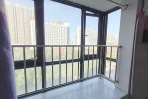 A room with a large window, a balcony with a metal railing, and a view of high-rise buildings. - Jiutian Business Hotel (Zhengzhou Shamen Subway Station) (Zhengzhou)