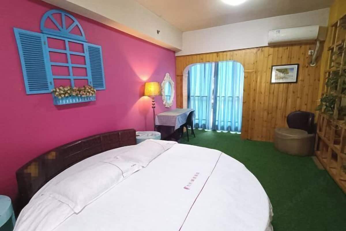 Ein Zimmer mit einem Bett, einem Schreibtisch, einem Stuhl, einem Fenster mit blauen Rollläden und einer Wandlampe.