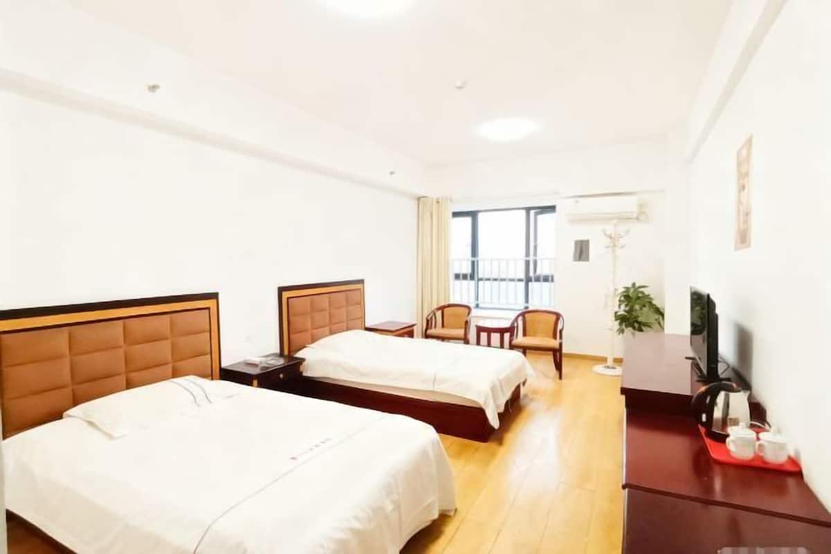 Ein Hotelzimmer mit zwei Betten, einem Schreibtisch mit Fernseher, einem Sessel und einem Balkon mit Aussicht.