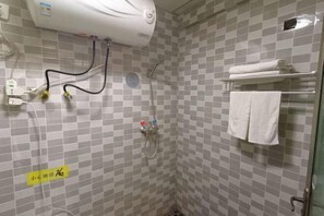 Ein Badezimmer mit Wandtäfelung aus Schachbrettfliesen, einem Handtuchhalter mit gefalteten Handtüchern und einer Dusche mit Duschbrause.
