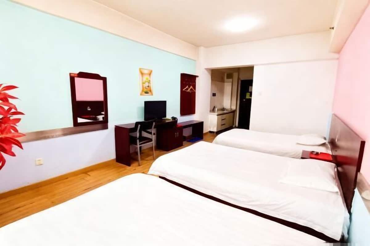 Ein Hotelzimmer mit zwei Betten, einem Schreibtisch mit Computer, einem Fernseher und einer roten Wanddekoration.