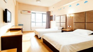 Une chambre d’hôtel avec deux lits, une télévision, un bureau et une fenêtre avec des rideaux.