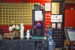 A reception desk with a digital display, a water dispenser, and a flower arrangement.
