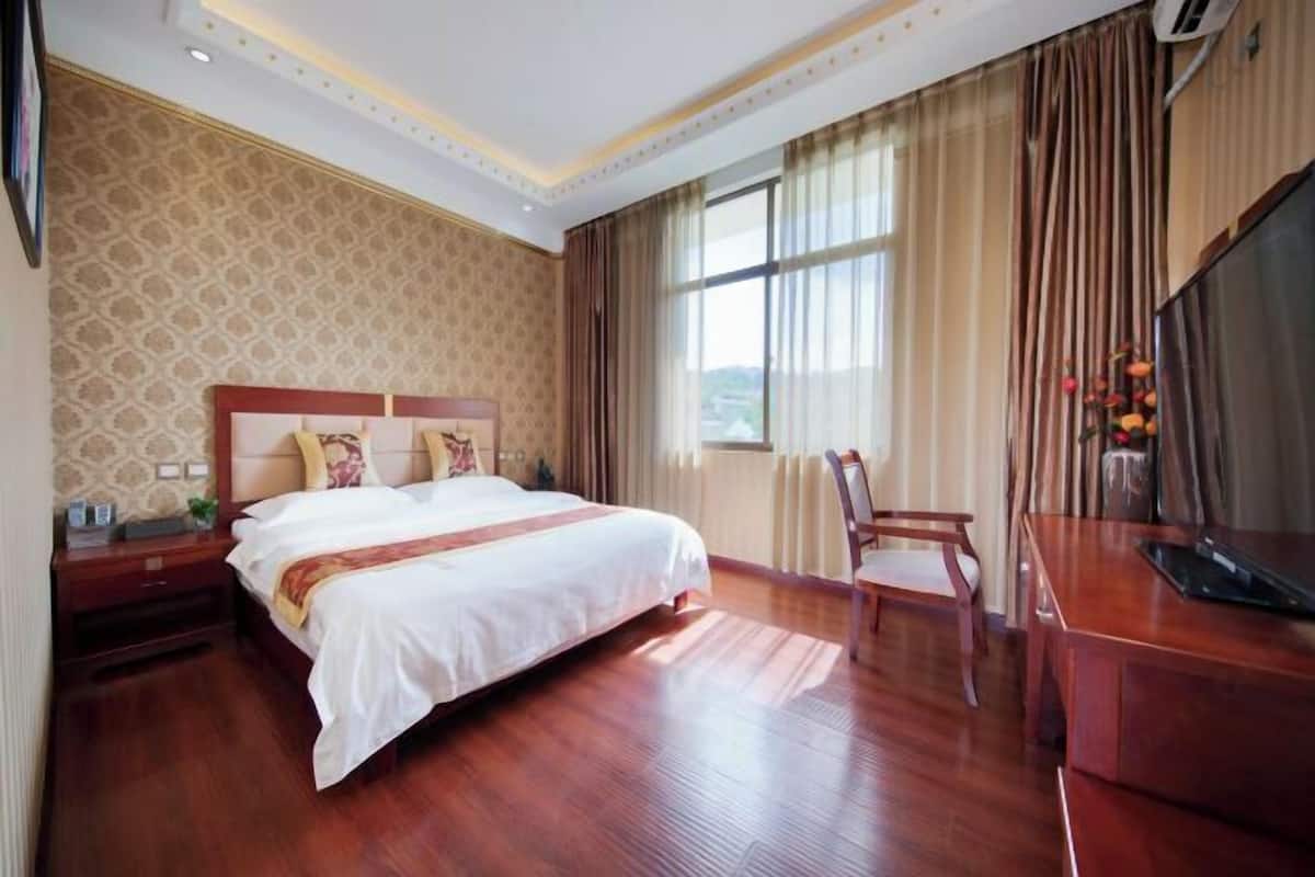 A hotel room with a large bed, a desk, and a TV.