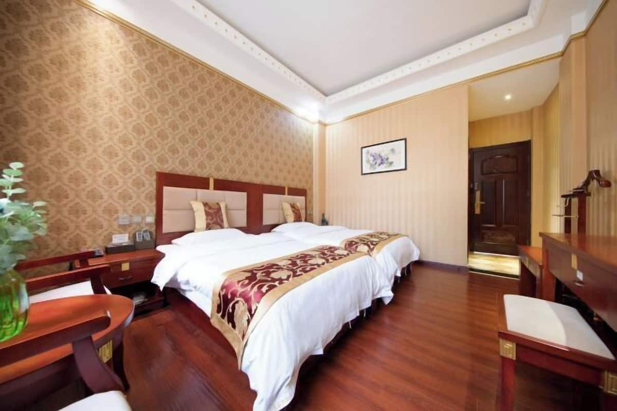 A hotel room with a large bed, wooden furniture, a desk, and a chair.