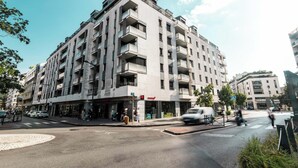A multi-story building with balconies, a pedestrian crossing, and a traffic light.