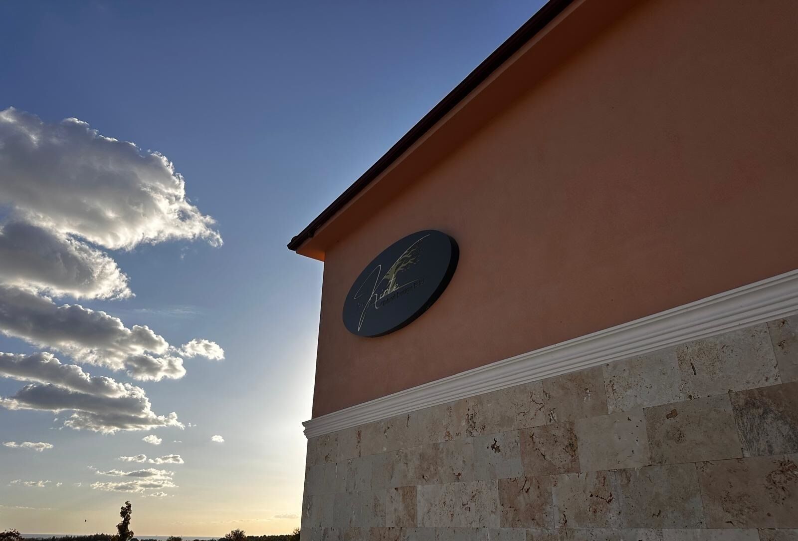 Un edifici amb façana de pedra i un signe circular a la paret.