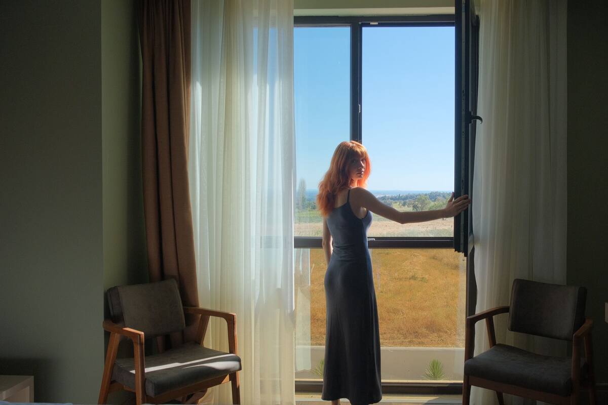 A room with a large window, two chairs, and a view of a landscape.