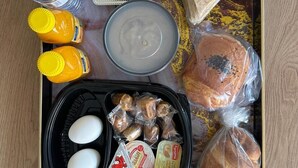 A tray with various food items including bread, olives, eggs, and packaged snacks. - Diamond corners Hotel (Madinah)