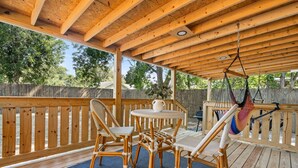 Un patio in legno con mobili in vimini e un'amaca sospesa.