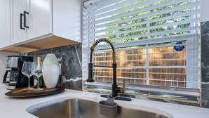 Una cucina moderna con lavello in acciaio inossidabile, portabicchieri per vino e un vaso decorativo.