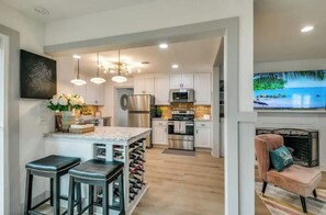 A modern kitchen with white cabinets, stainless steel appliances, and a wine rack. - East Dallas 3 Bedroom Home With Stunning Backyard Oasis (Dallas)