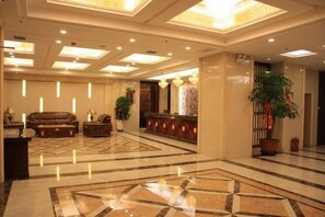 Un hall d’hôtel comprenant un comptoir d’accueil, un espace salon et une grande plante décorative.