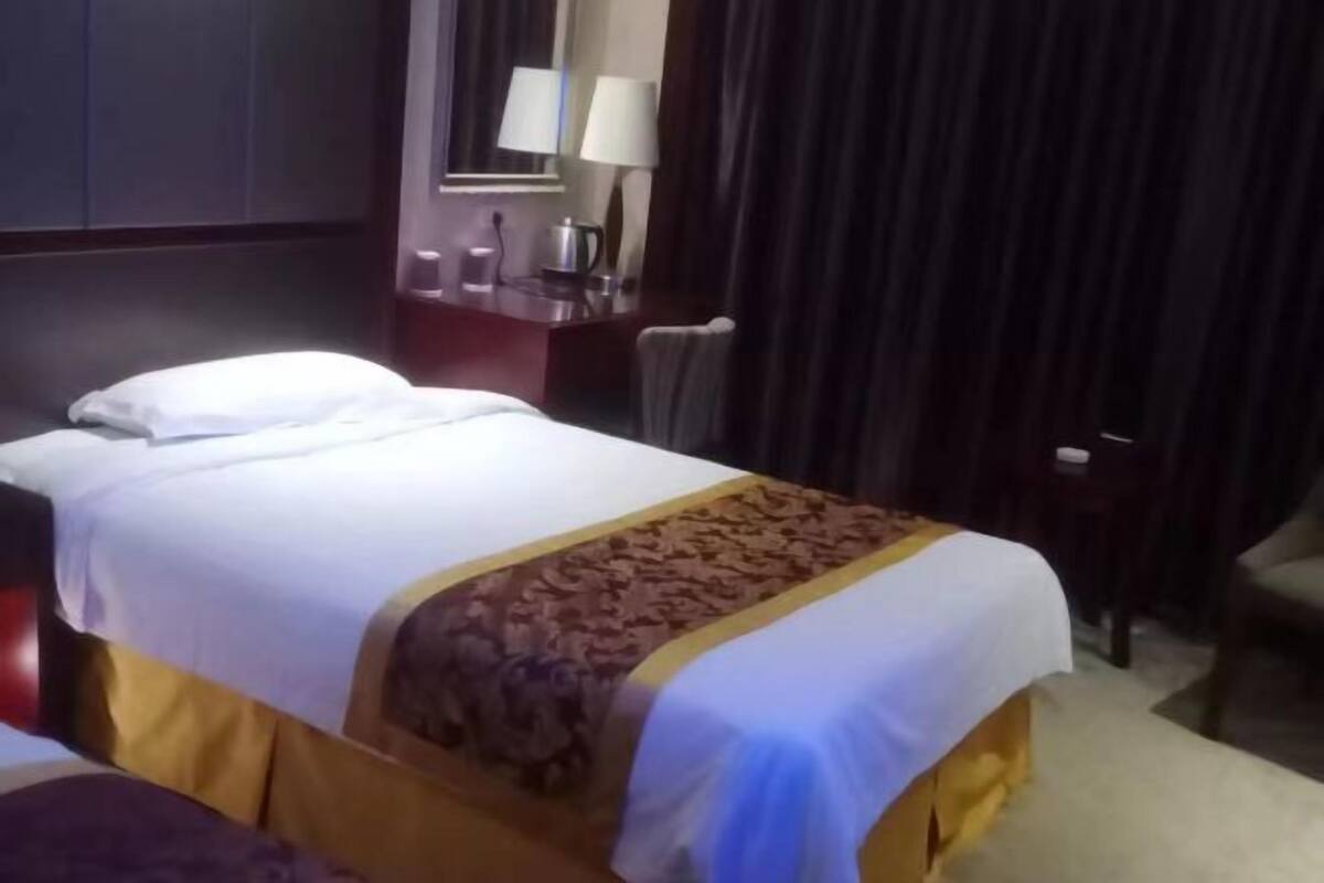 A hotel room with a bed, a nightstand with a lamp, and a chair.
