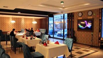 Un restaurant avec des tables dressées, un écran de télévision et une vue sur la rue.