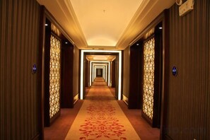 A hotel corridor with a carpeted floor, doors on both sides, and a patterned wall design. - Huilong Business Hotel (Fuyuan)