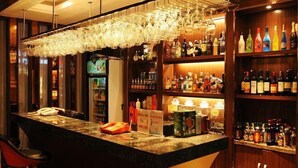 Baarialue, jossa on tiski, hyllyt täynnä alkoholijuomapulloja ja seinälle ripustettu lasiteline.