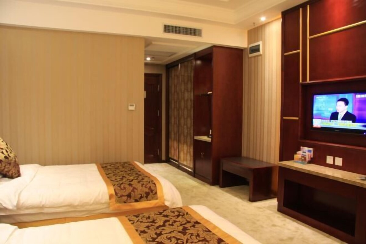 Ein Hotelzimmer mit zwei Betten, einem Fernseher und einem Kleiderschrank.
