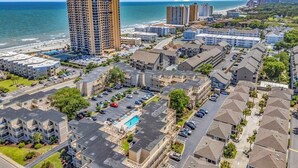 A coastal residential area with a large hotel, a swimming pool, and a beach in the background. - Private & Comfy Oasis: 5-star, Ocean View, Pool, Near Golf ~ Free Parking! (Myrtle Beach)