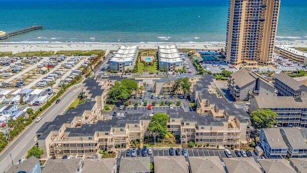 A coastal hotel with multiple buildings, a parking lot, and a beach view. - Private & Comfy Oasis: 5-star, Ocean View, Pool, Near Golf ~ Free Parking! (Myrtle Beach)