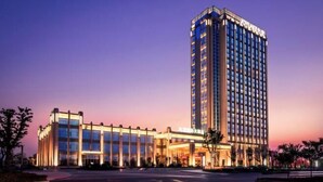 Un hotel moderno con una torre destacada y un edificio más bajo con fachada de vidrio.