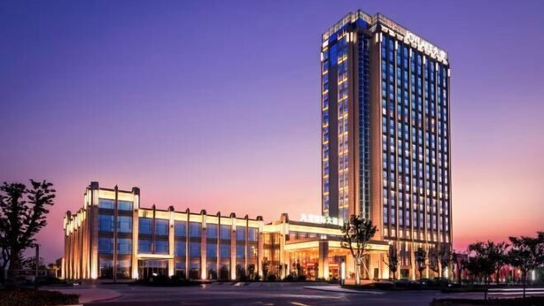 Een modern hotel met een opvallende toren en een lager gebouw met een glazen gevel.