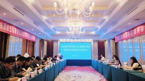Un salón de conferencias con una larga mesa, sillas y una pantalla al frente.
