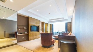 Una habitación de hotel moderna con televisión de pantalla plana, un sofá, una mesita de café y un cubo de basura.