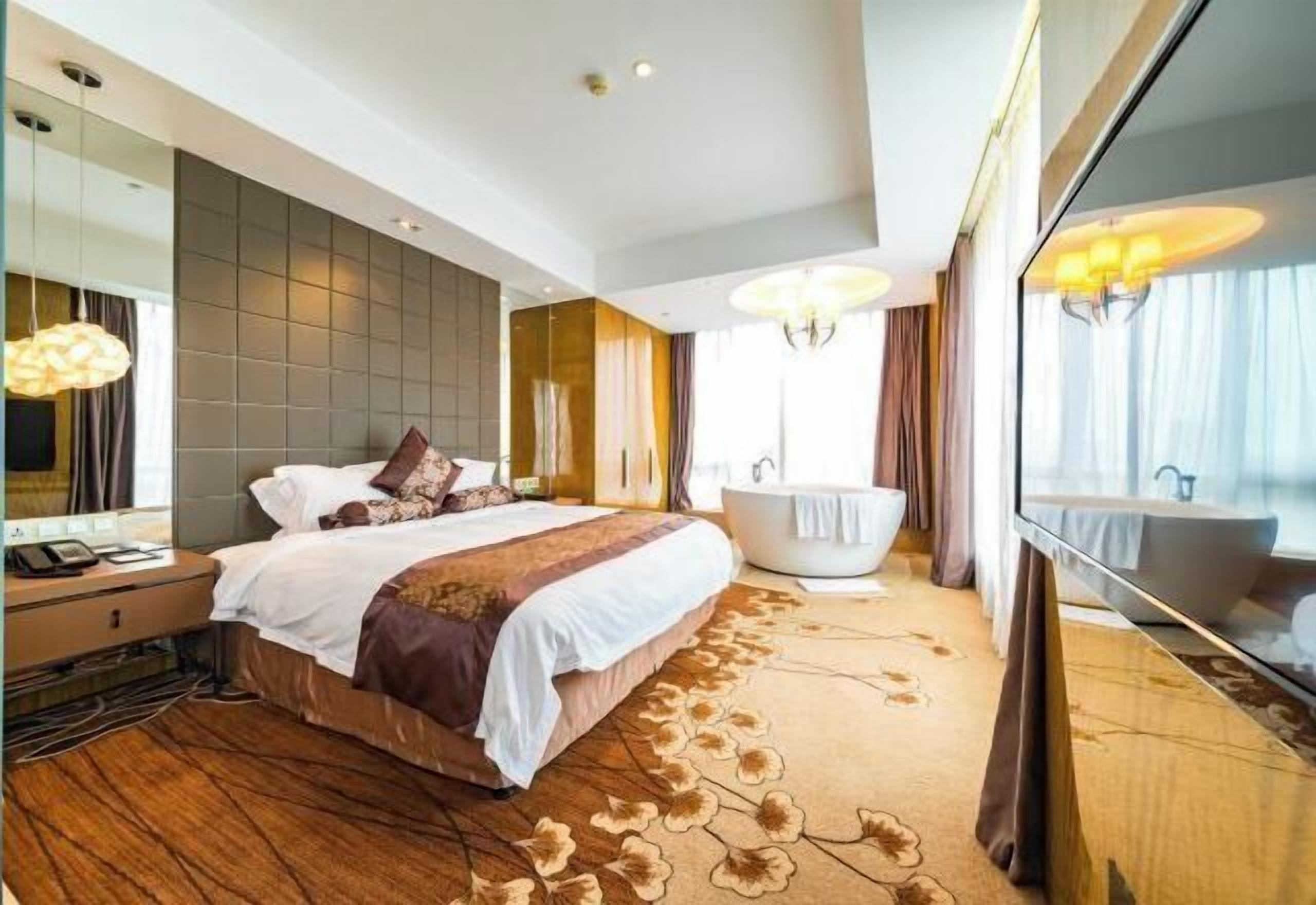 A modern hotel room with a large bed, a bathtub, a large mirror, and a view of the city.