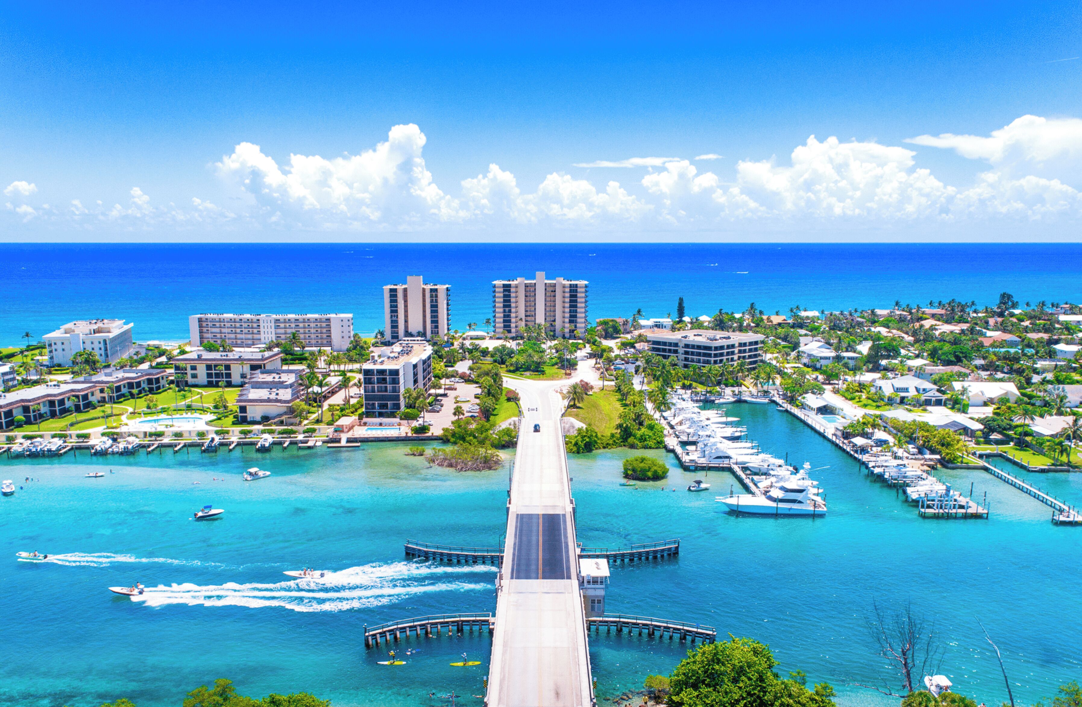A coastal resort with a marina, a bridge connecting the mainland to the island, and high-rise buildings in the background.
