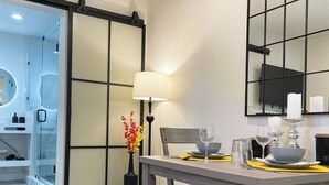 A dining area with a table set for two, a vase with flowers, a lamp, and a mirror on the wall. - Luxury, Private Suite in cool Palm Beach Gardens with WiFi, AC (Palm Beach Gardens)